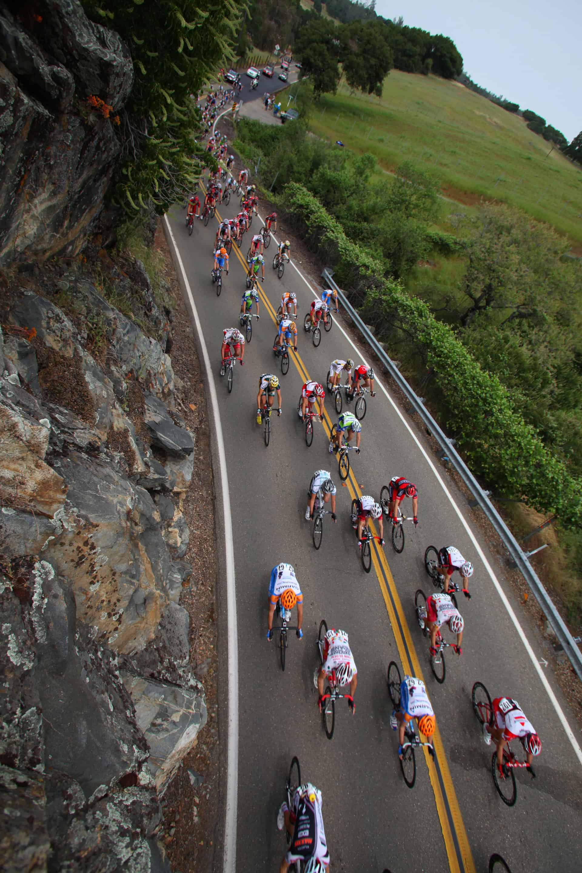 <p>This was one of the most difficult images I took. I found this rock wall when we were out ahead of the Peloton. There was no shoulder on the edge of the road so my driver left me there and I climbed up that rock wall with my camera bag on my back. I didn’t have much time to get ready and they came by quickly. After they pass there’s about two miles of solid back-up support teams driving as fast as they can in trucks, cars and vans. I had to climb back down that rock cliff. One slip and I was on the road with nonstop moving traffic. That’s when it got scary.</p>
